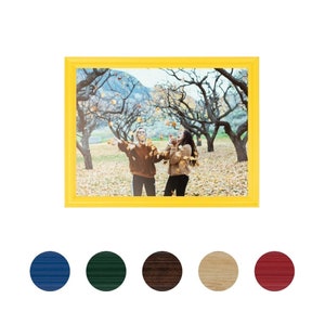 May include: Two friends laughing and throwing leaves in the air in a yellow picture frame. The frame is on a white background.