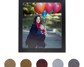 May include: A black picture frame with a photo of a woman and a child holding balloons. The woman is wearing a black jacket and a red scarf. The child is wearing a red shirt and blue jeans. The balloons are red, orange, blue, and green.