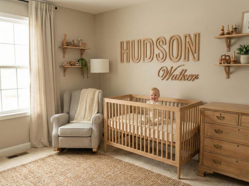 Puede incluir: Una habitaci&oacute;n infantil con una cuna de madera, una c&oacute;moda y estanter&iacute;as. El nombre "HUDSON Walker" se muestra en la pared. Un beb&eacute; est&aacute; sentado en la cuna. La habitaci&oacute;n tiene una paleta de colores neutros con una alfombra y una mecedora.