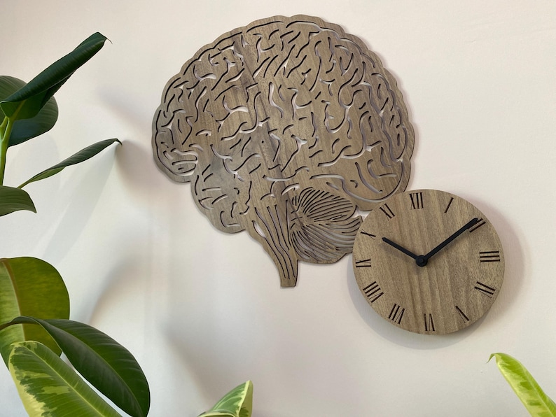 Puede incluir: Un reloj de pared de madera con forma de cerebro humano con n&uacute;meros romanos en la esfera.