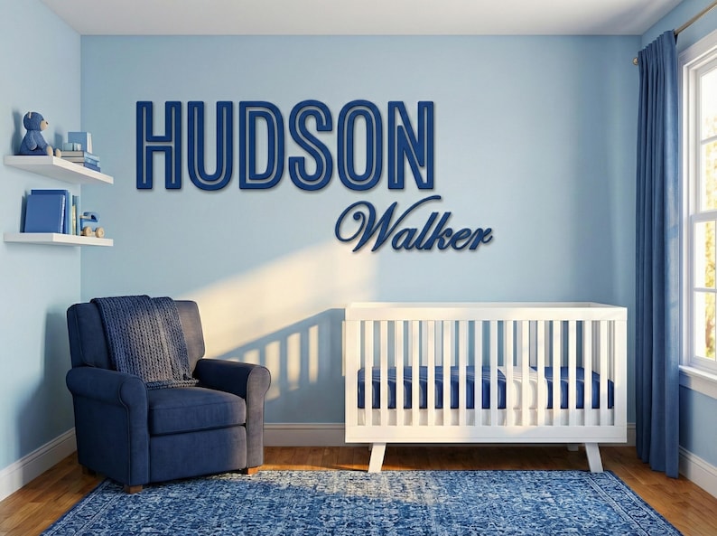 Puede incluir: Un cuarto de beb&eacute; con una tem&aacute;tica azul y blanca. La pared presenta el nombre "HUDSON" sobre el nombre "Walker" en una fuente cursiva. Una cuna blanca, un sill&oacute;n azul y una alfombra azul completan la habitaci&oacute;n.