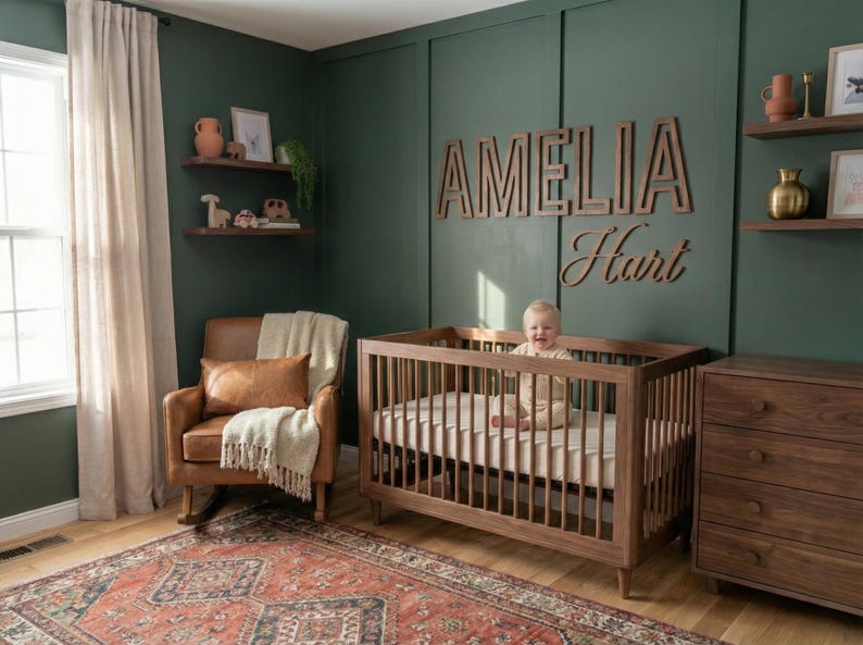 Puede incluir: Una guarder&iacute;a con una cuna de madera, una c&oacute;moda y una mecedora. Las paredes est&aacute;n pintadas de verde oscuro y la habitaci&oacute;n est&aacute; decorada con estanter&iacute;as de madera y una alfombra. El nombre "Amelia Hart" se muestra en la pared.