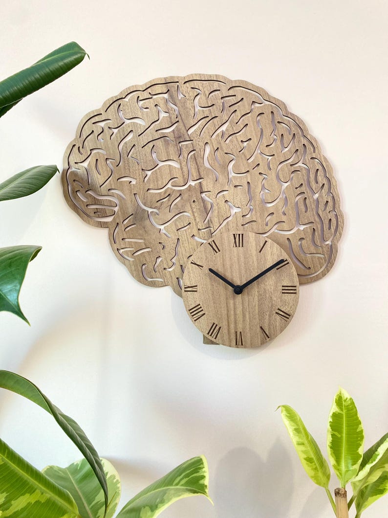Puede incluir: Un reloj de pared de madera con forma de cerebro con n&uacute;meros romanos. La esfera del reloj est&aacute; en el centro de la forma del cerebro.