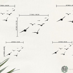 Puede incluir: Un conjunto de calcoman&iacute;as de pared de p&aacute;jaros negros en silueta. Las calcoman&iacute;as est&aacute;n dispuestas en diferentes tama&ntilde;os y posiciones para crear una bandada de p&aacute;jaros en vuelo. Las calcoman&iacute;as se muestran en una pared blanca con medidas en pulgadas y cent&iacute;metros.