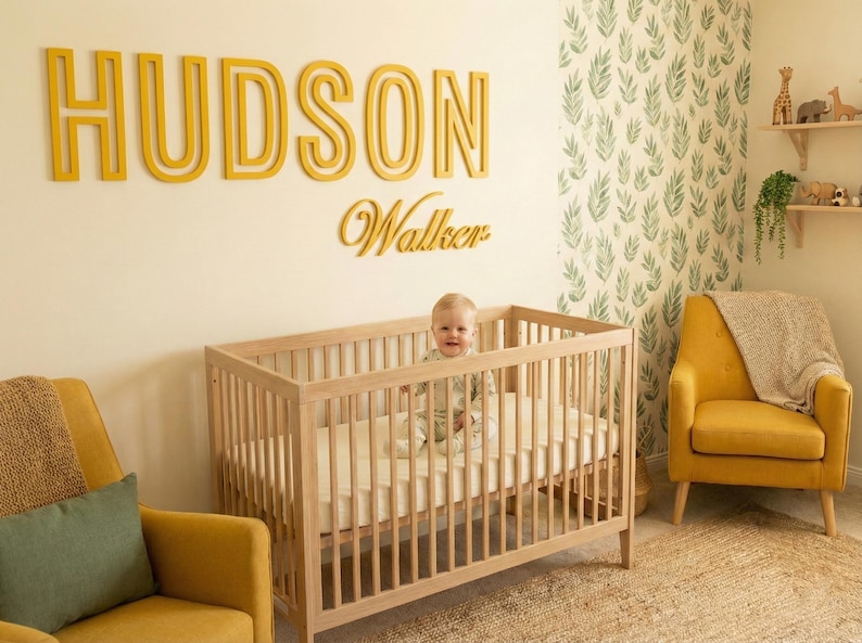 Puede incluir: Una escena de guarder&iacute;a con una cuna de madera y un beb&eacute; dentro. Encima de la cuna, el nombre "HUDSON" y el nombre "Walker" se muestran en letras amarillas. La habitaci&oacute;n tiene sillones amarillos y un papel pintado con estampado de hojas verdes y blancas.
