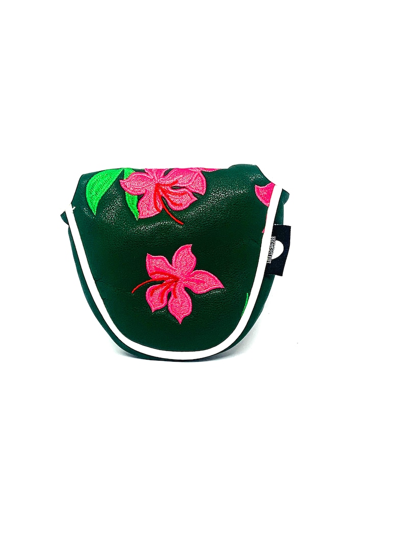 May include: Dark green golf putter cover with embroidered pink hibiscus flowers and green leaves. The cover has a white trim and a small black tag on the side.