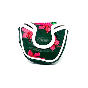 May include: Dark green golf putter cover with a white border and a vibrant pink floral design. The cover is made of a textured material and has a magnetic closure. The putter cover is designed to protect the golf club head.