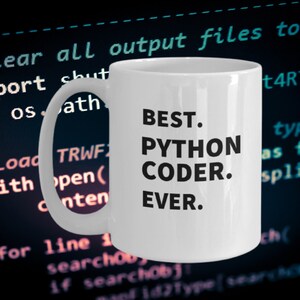 May include: A white ceramic mug with a handle on the left side. The mug features black text printed on the front that reads: BEST. PYTHON CODER. EVER. The background displays a blurred computer screen showing lines of programming code.