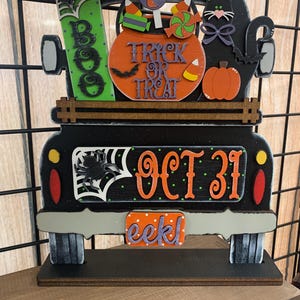 May include: Black wooden truck with a black cat, a pumpkin, candy, and a sign that says "Trick or Treat". The truck has a license plate that says "eek!" and the date "Oct 31" on the back.
