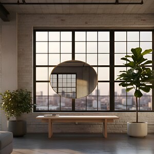 May include: A modern interior with a large window overlooking a cityscape. A round, gold-framed mirror hangs in front of the window. A light wood bench and potted plants are in the room. The walls are white brick.