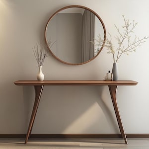 May include: A modern, minimalist interior scene featuring a wooden console table with a round mirror above it. The table has a sleek design with curved legs. Decorative vases with branches and small bottles add a touch of elegance to the space.