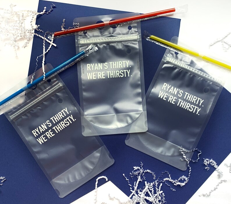 Puede incluir: Tres bolsas de pl&aacute;stico transparentes con cierre de cremallera. Cada bolsa tiene el texto "Ryan's Thirty. We're Thirsty." impreso en blanco.