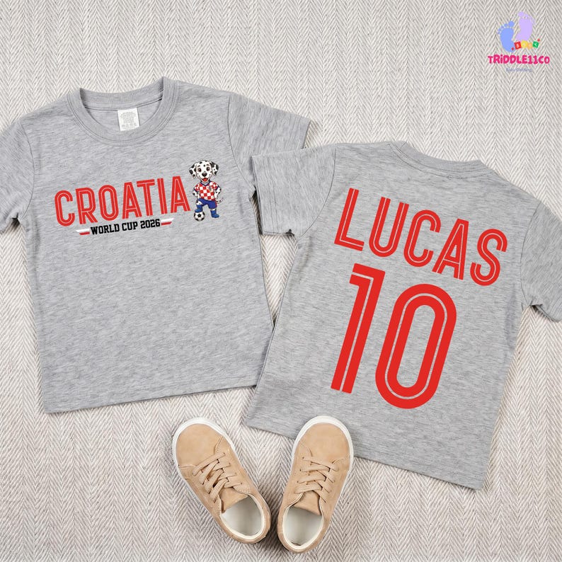 May include: Two heather gray short-sleeve t-shirts. The left shirt features the red text CROATIA, the text WORLD CUP 2026, and a dalmatian mascot graphic. The right shirt features the red text LUCAS and the number 10 in a bold, outlined font.
