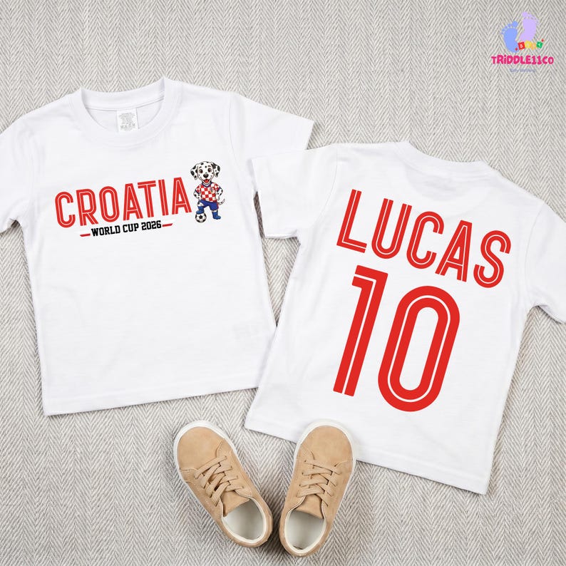 May include: Two white short-sleeved t-shirts. The first shirt features the red text CROATIA WORLD CUP 2026 and a cartoon dalmatian playing soccer. The second shirt displays the red text LUCAS and the number 10 in a bold, outlined font.