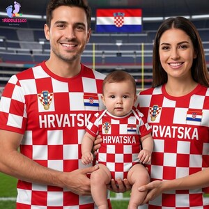 May include: A matching set of red and white chequered shirts and a baby bodysuit featuring the Croatian national emblem, the text HRVATSKA, and a small Croatian flag. The garments display a consistent red and white square pattern throughout.