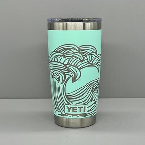 K&ouml;nnte beinhalten: Ein t&uuml;rkisfarbener YETI-Becher mit einem schwarz-wei&szlig;en Wellendesign. Der Becher hat einen Deckel und einen Boden aus Edelstahl.