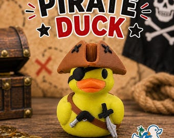 May include: A yellow rubber duck figurine dressed as a pirate, wearing a brown tricorn hat and a black eye patch. The duck features a brown shoulder strap holding a small silver sword and a black pistol. Text above reads PIRATE DUCK.