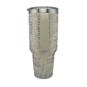 K&ouml;nnte beinhalten: Ein wei&szlig;er Edelstahlbecher mit schwarzem Griff. Der Becher ist mit einem Camping-Motiv verziert und zeigt verschiedene Camping-bezogene Illustrationen und Texte, darunter "Camping Crew", "Life is Better Around Campfire" und "Need to Go Camping".