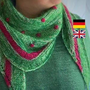 Könnte beinhalten: Ein grüner und pinkfarbener Strick Schal mit weißen Flecken und roten Punkten. Der Schal ist um den Hals einer Person gelegt, die einen grünen Pullover trägt.