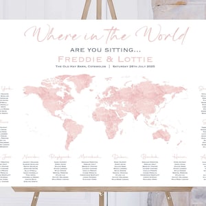 May include: A wedding seating chart with a pink watercolor world map and a list of guest names organized by city. The text at the top reads "Where in the World Are You Sitting... Freddie & Lottie The Old Hay Barn, Cotswolds | Saturday 26th July 2023"
