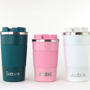 Op de afbeelding: Drie gepersonaliseerde reistassen met roestvrijstalen deksels. De tassen zijn teal, roze en wit met de namen "James", "Rosie" en "Jadzia" gedrukt op de bodem.