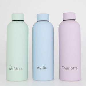 May include: Three stainless steel water bottles with personalised names. The bottles are light green, light blue, and light purple. The names are "Rakhee", "Aydin", and "Charlotte".