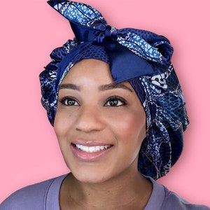 Puede incluir: Un gorro de dormir de satén azul y blanco con un lazo de satén azul marino. El gorro está diseñado para proteger el cabello mientras se duerme.