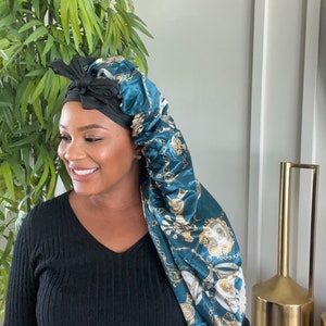 May include: A teal satin sleep cap with a gold chain print. The cap is tied with a black satin ribbon.