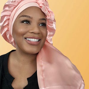 Puede incluir: Un gorro de sat&eacute;n rosa con un lazo en la parte superior. El gorro est&aacute; dise&ntilde;ado para proteger el cabello mientras se duerme.