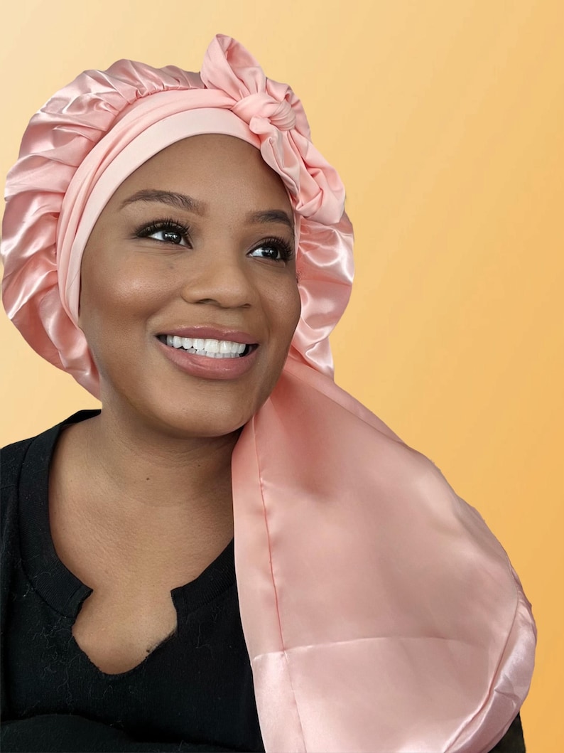 Puede incluir: Un gorro de sat&eacute;n rosa con un lazo en la parte superior. El gorro est&aacute; dise&ntilde;ado para proteger el cabello mientras se duerme.