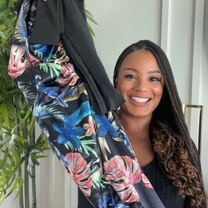 May include: A black long-sleeved shirt with a floral print. The print features large tropical leaves in shades of blue, green, red, and yellow on a black background.
