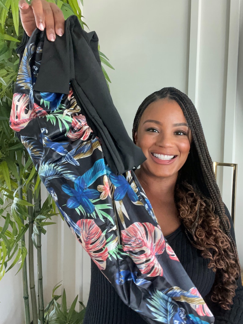 May include: A black long-sleeved shirt with a floral print. The print features large tropical leaves in shades of blue, green, red, and yellow on a black background.