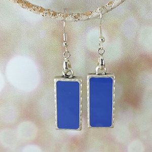 Könnte beinhalten: Ein Paar silberne Ohrhänger mit einem rechteckigen blauen Emaille-Anhänger. Die Ohrringe haben ein schlichtes Design und sind perfekt für den Alltag.