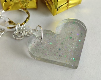 May include: A silver key chain with a clear heart-shaped charm filled with iridescent glitter.