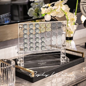 May include: A clear acrylic game board with black and white game pieces. The board is on a black tray with a gold trim. The tray is on a grey surface. The text "Remarkable" is visible on the tray.
