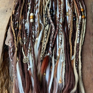 May include: A set of brown, white, and beige synthetic dreadlocks with beads and charms. The dreadlocks are approximately 20 inches long.