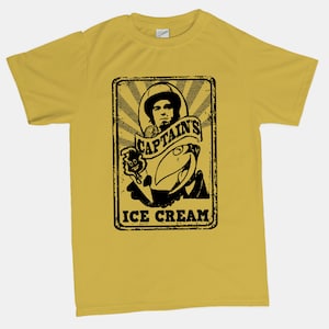 May include: A yellow t-shirt featuring a black and white graphic print of a man holding an ice cream cone. The graphic reads "Captain's Ice Cream".