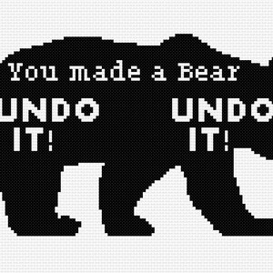 Könnte beinhalten: Ein schwarzes Kreuzstichmuster einer Bärensilhouette auf einem weißen Rasterhintergrund. Der Text "You made a Bear" steht oben, gefolgt von den Wörtern "UNDO IT!", die zweimal in weißer, blockartiger, verpixelter Schrift im Bären abgebildet sind.