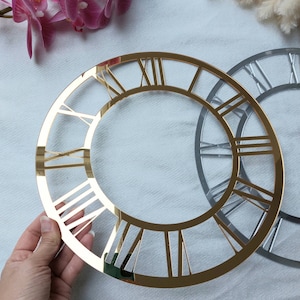 Könnte beinhalten: Gold- und silberfarbener, verspiegelter Ziffernblatt mit römischen Ziffern. Das Ziffernblatt ist ein dekoratives Stück für eine DIY-Uhr.