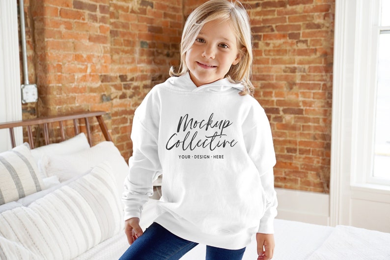 Pu&ograve; includere: Una felpa con cappuccio bianca con il testo "Mockup Collective" e "Your Design Here" stampato sul davanti. Una persona giovane indossa la felpa.