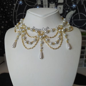 May include: A gold-toned choker necklace with multiple strands of faux pearls and delicate chains. The necklace features a cascading design with teardrop-shaped pearl pendants. The text "Raven.Craft" is visible on the image.