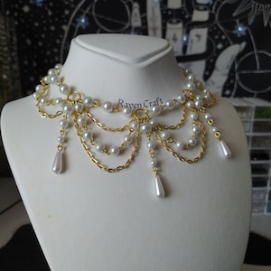 May include: A pearl and gold-tone necklace displayed on a white mannequin. The necklace features multiple strands of small, round white pearls connected by delicate gold chains. Teardrop-shaped pearl pendants hang from the bottom. The text "Raven.Craft" is visible.