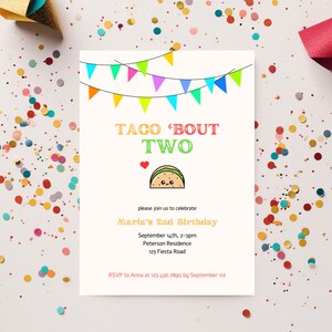 Pode incluir: Um convite creme com o texto "TACO 'BOUT TWO" em letras coloridas, uma ilustração de taco e detalhes da festa. O convite inclui uma guirlanda de bandeirinhas coloridas e confetes.