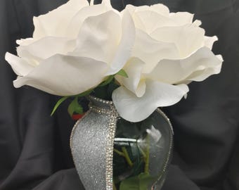 May include: A silver glitter vase with rhinestones around the rim, holding white roses.