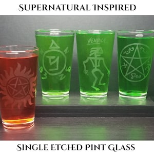 May include: Four etched pint glasses with different Supernatural symbols. The glass on the left has a red liquid and features the anti-possession symbol. The other three glasses have green liquid and feature the symbols for "Wendigo", "Devil's Trap", and a sigil.