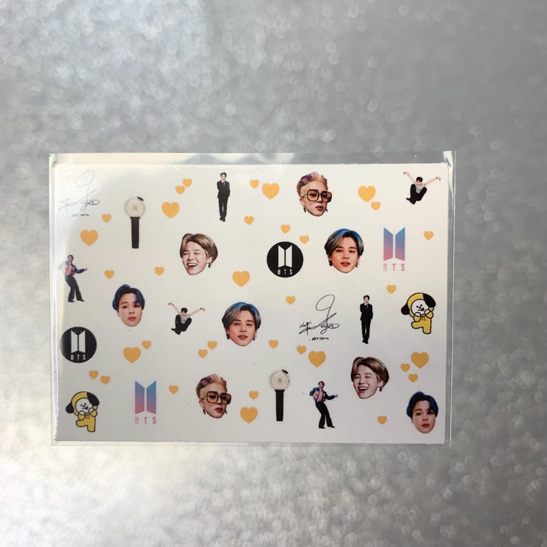 May include: A sheet of stickers featuring images of a musical group. The stickers include portraits, logos, and signatures, along with yellow heart and light stick graphics. The stickers are on a white background.