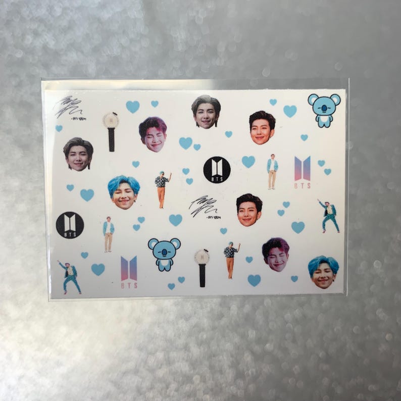May include: A sheet of stickers featuring images of people, hearts, and logos. The stickers have a white background with blue hearts scattered throughout. The images include faces, logos, and figures in various poses. The stickers are in a clear plastic sleeve.