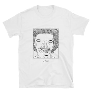 May include: A white t-shirt with a black and white line drawing of a person with an afro hairstyle. The drawing is in a square frame with the word "ERIC" printed below the frame.