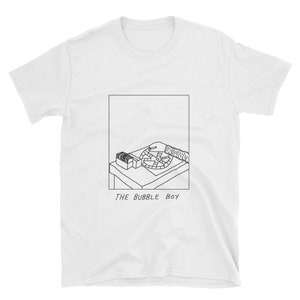 May include: A white t-shirt with a black and white illustration of a hand reaching into a box and spinning a wheel. The text "THE BUBBLE BOY" is printed below the illustration.