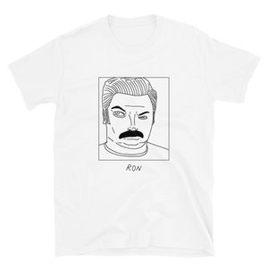 May include: A white t-shirt featuring a black line drawing of a man's face with a moustache. The text "RON" is beneath the drawing.
